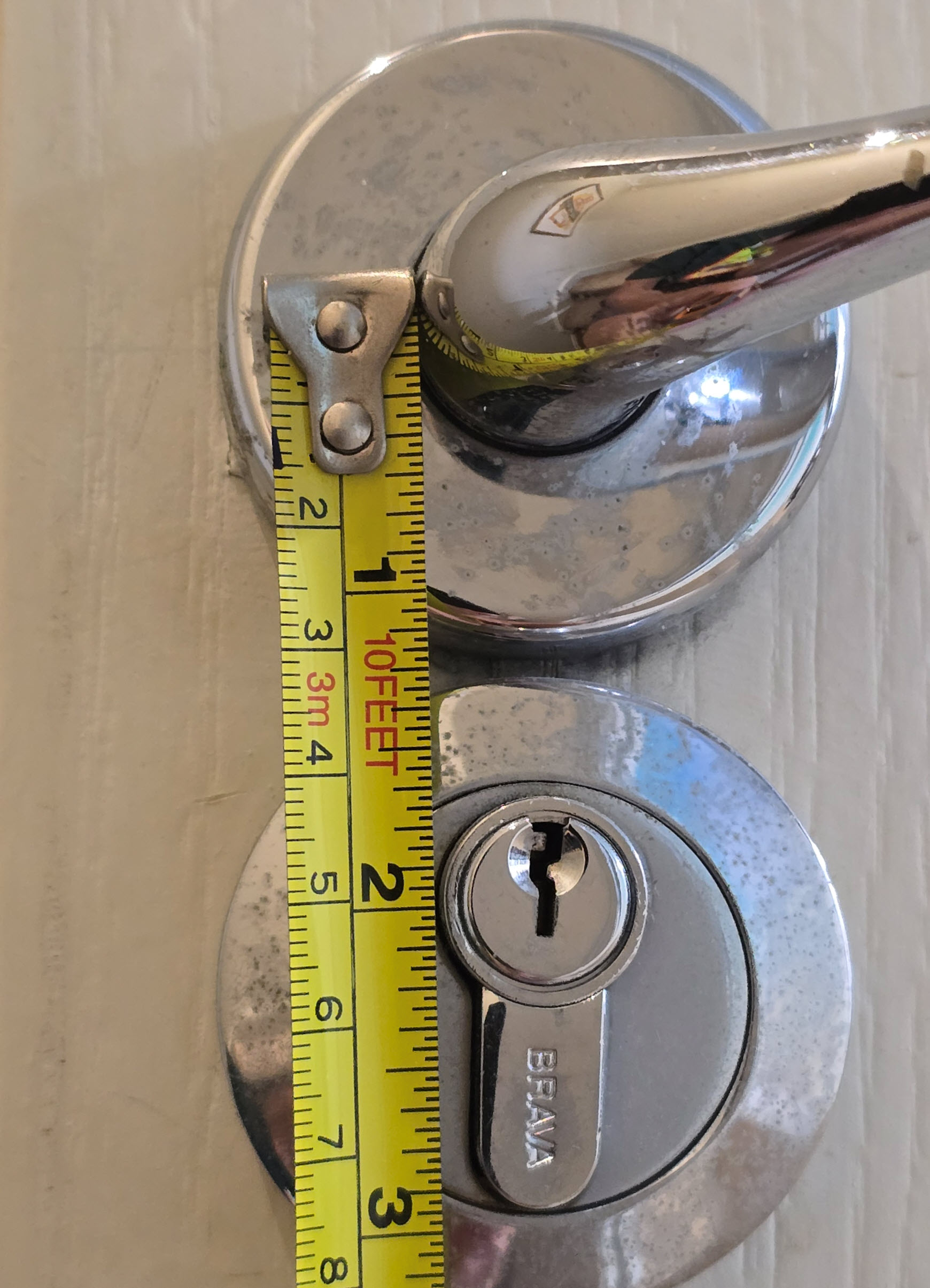 Tape measure running vertically from the lever handle down past the euro cylinder to show the handle-to-cylinder centres, known as pitch